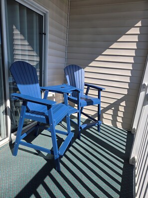 A balcony with two blue Adirondack chairs and a small table. - Sandpiper Bay 3rd Floor. 4 mi to beach. 3 bd, 2 ba, new kitchen,  pool & more (Sunset Beach)