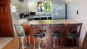 Una cocina con una isla central, taburetes de bar, un refrigerador y una ventana con vistas.