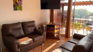 Una sala de estar con un sofá de cuero marrón, un televisor de pantalla plana y un mueble de madera.