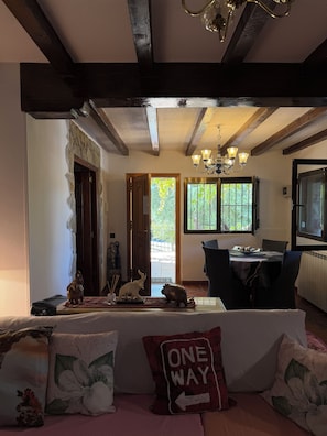 A cozy living room with a sofa, a dining table, and a chandelier. - Apartment in a country house with a pool near Madrid | Children and pets welcome (Sotolargo)