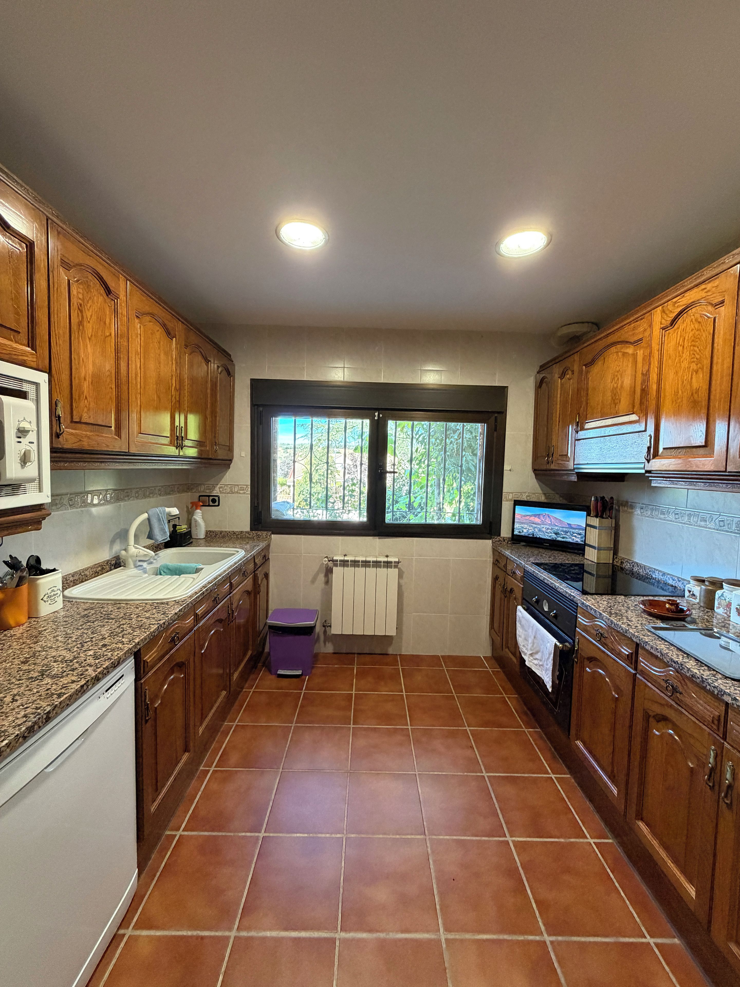 Una cocina con armarios de madera, encimera de granito, ventana con vistas y horno empotrado.