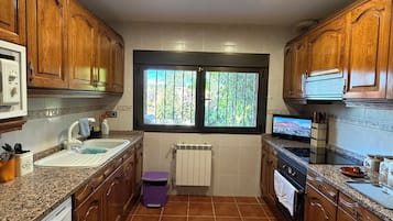 Una cocina con armarios de madera, encimera de granito, ventana con vistas y horno empotrado.