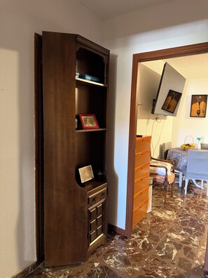 A room with a wooden cabinet, a dining table with chairs, and a tiled floor. - Apartment in a country house with a pool near Madrid | Children and pets welcome (Sotolargo)