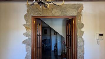 Un arco de piedra que da acceso a un pasillo con una araña y un teléfono en la pared.