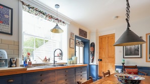 A kitchen with a wooden table, a sink, and a blue cabinet. - Church Garden Apartment (Malvern)