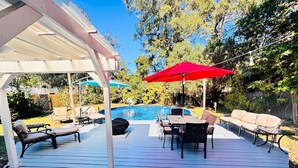 Eine überdachte Terrasse im Freien mit Pool, Liegestühlen und Tisch.