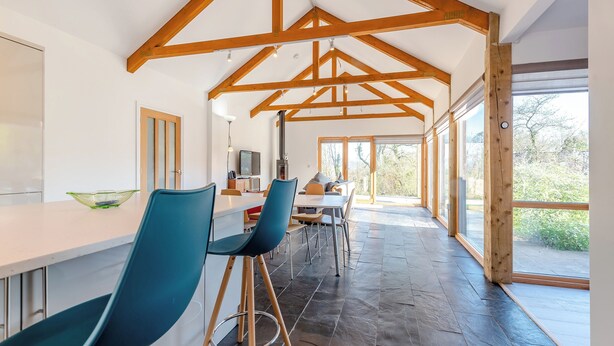 A modern kitchen with a white countertop, blue chairs, and a large window. - 1 bedroom accommodation in Llandeilo (Llandeilo)