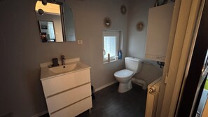 Une salle de bain avec un lavabo blanc, des toilettes et un miroir au mur.