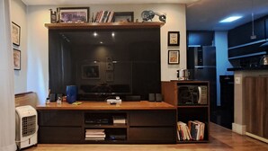A modern living room with a wooden entertainment center, a flat-screen TV, and a built-in bookshelf.