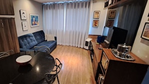 A compact living space with a dining table, sofa, and a kitchenette area.