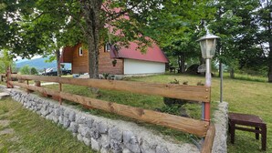 Una casa de madera rústica con techo rojo, pared de piedra y cerca de madera.