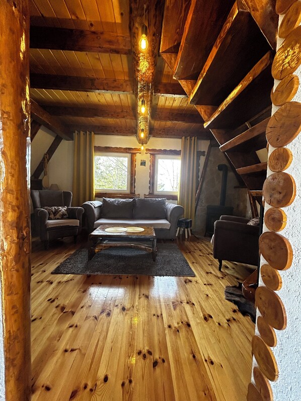 A cozy log cabin interior with a wooden floor, a sofa, a coffee table, and a fireplace. - Vila Sarigora - charming 2-bedroom cottage in fabulous Žabljak (Žabljak)