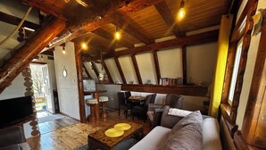Una sala de estar acogedora con techo de madera, un sofá, una mesa de centro y un comedor con sillas y una mesa.