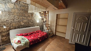A room with a bed, a stone wall, a wooden ladder, and a door. - Apartment central near Herbstmesse & Baloise Session (Basel)