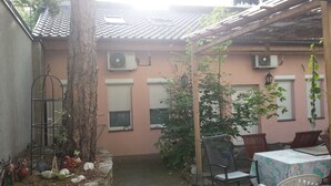 A covered patio area with a table and chairs, a tree, and a metal birdcage. - Apartment central near Herbstmesse & Baloise Session (Basel)