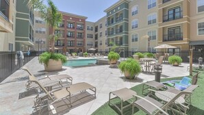 Une cour avec une piscine, des chaises longues et des plantes en pot.