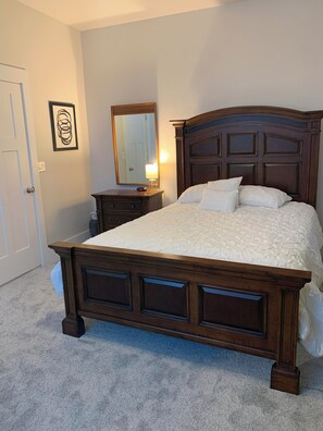 Un dormitorio con una cama grande, un aparador, un espejo y una puerta.
