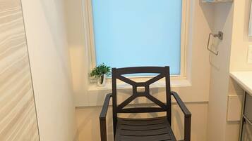 A bathroom with a window, a chair, a towel rack, and a small plant.