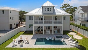 A two-story house with a swimming pool, outdoor seating, and a fenced yard. - Luxe Beach Retreat Walk to Beach Pool Spa, Golf Cart, Game Room & Putting Green (Santa Rosa Beach)