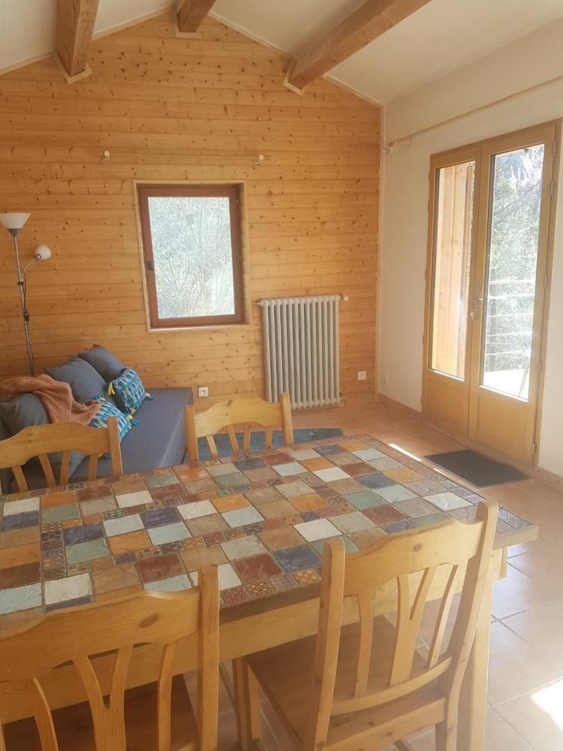 Una habitación acogedora con piso de madera, una mesa a cuadros y un sofá con cojines.