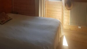 A wooden cabin room with a bed, a window, and a radiator.