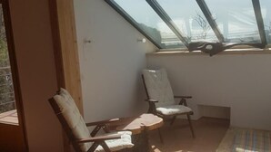 A sunlit room with a sloped ceiling, wooden furniture, and a view through a skylight.