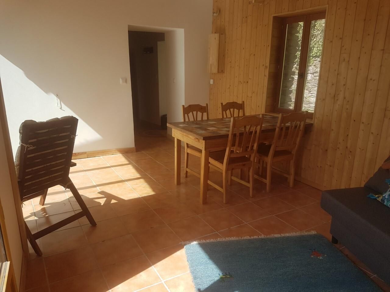 Una stanza con un tavolo e sedie in legno, un tappeto blu e un divano.