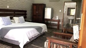 Un dormitorio con cama, armario, una mesita y espejo.