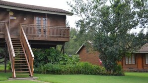 Una cabaña de madera con balcón, una escalera y un pequeño jardín.