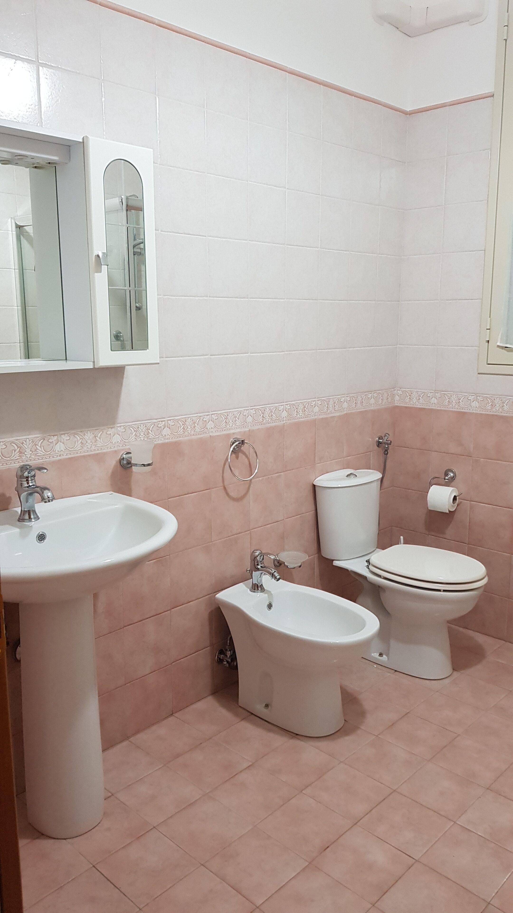 A bathroom with a sink, bidet, toilet, and mirror.