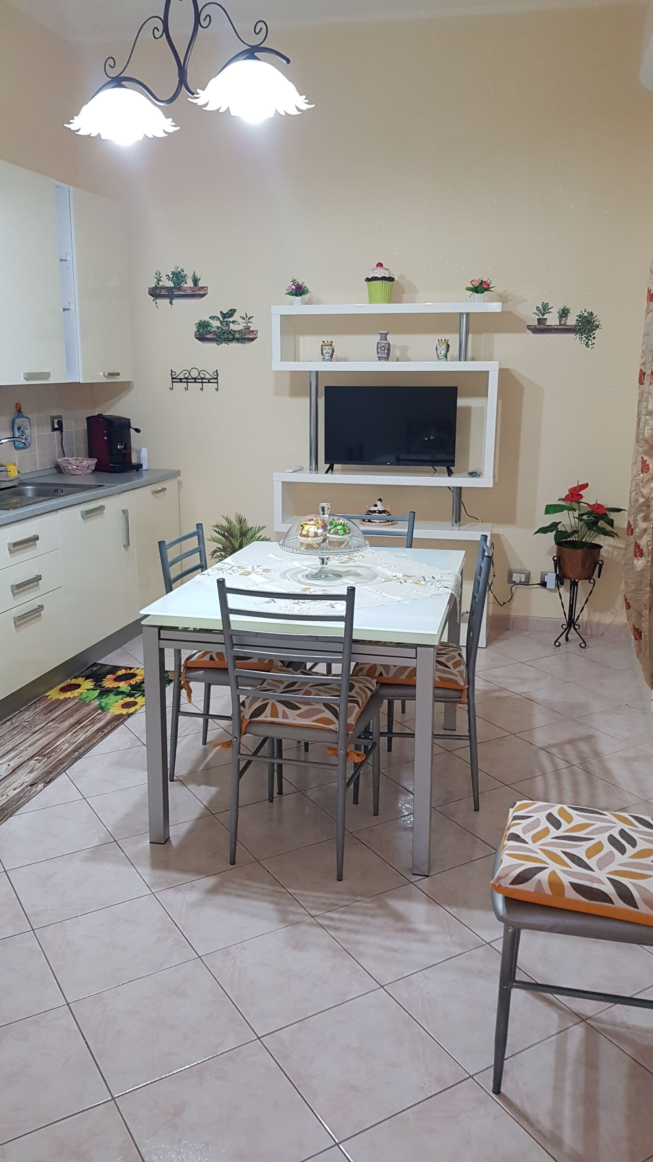 Een eethoek met een tafel, stoelen, een televisie en decoratieve items aan de muur.