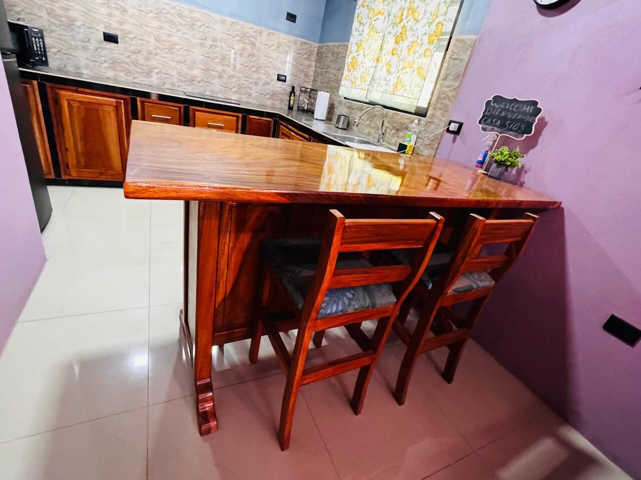 A kitchen with a wooden bar counter and four chairs.