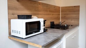 A kitchen with a white microwave on a granite countertop, a wooden backsplash, and a black coffee maker. - Cosy loft in the heart of Cambrai (Cambrai)