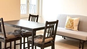 Een eetgedeelte met een tafel en stoelen, een bank met kussen en een raam met uitzicht.