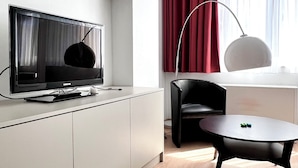 A modern living room with a flat-screen TV, a black chair, a round table, and a red curtain. - Studio Apartment Heart of Brussels (Brussels)