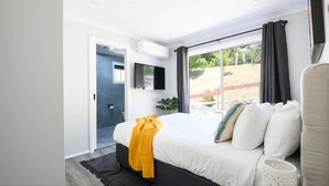 A modern bedroom with a large bed, a TV, and a view of the outdoors. - Lake Cove Daylesford (Daylesford)