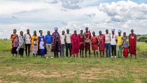 A group of people standing in a grassy field with a clear sky and clouds in the background. - Kapoto Camp (Maasai Mara)