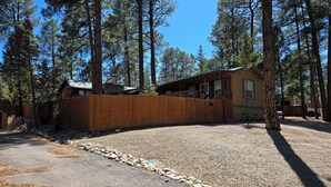 A two-story building with a fenced yard, surrounded by tall pine trees.