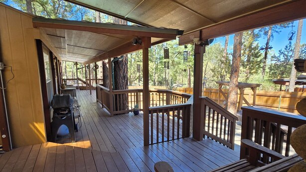 A wooden deck with a covered area, benches, and a grill.