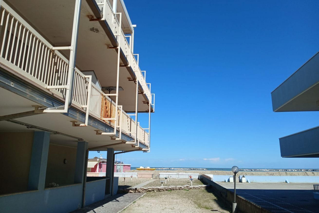 A multi-story building with balconies overlooking a beach.