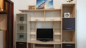 Et moderne tv-møbel med fjernsyn, hylder og opbevaringsrum.