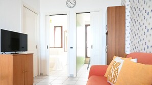 Una sala de estar con televisión, un sofá, un mueble de madera y una pared con diseño.