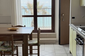 A dining area with a view of the sea, a kitchen with a sink, and a door leading to a balcony. - P056 – Porto Recanati, comfortable three-room apartment facing (Porto Recanati)