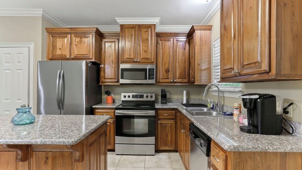 A kitchen with wooden cabinets, stainless steel appliances, granite countertops, and a built-in oven. - Charming 3-bedroom house located minutes from LSU (Baton Rouge)