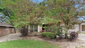 A residential house with a brick exterior, a front yard with a small tree, and a garage. - Charming 3-bedroom house located minutes from LSU (Baton Rouge)