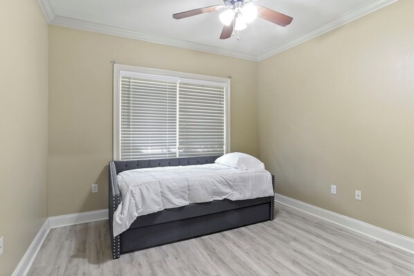 A bedroom with a bed, a ceiling fan, and a window with blinds.