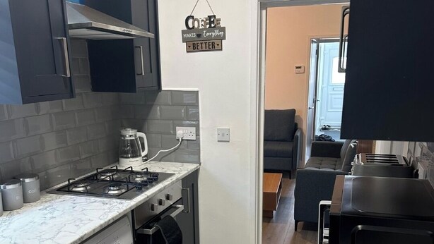 A compact kitchen with a gas stove, a built-in oven, a washing machine, and a microwave.