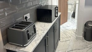 A modern kitchen with dark cabinets, a marble countertop, a toaster, and a microwave.