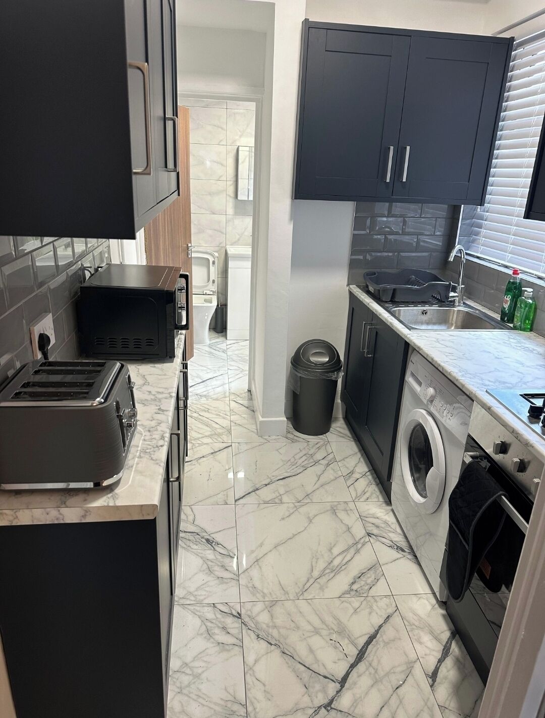 A compact kitchen with a built-in washing machine, a toaster, and a sink.