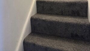 A staircase with carpeted steps and a metal handrail.